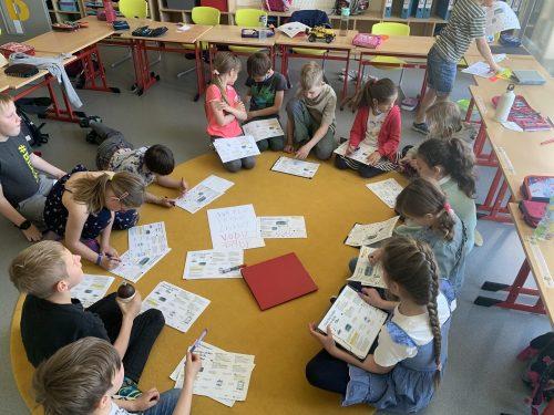 Děti ve škole pracujícící s pracovními listy na téma uzavřený cyklus jídla